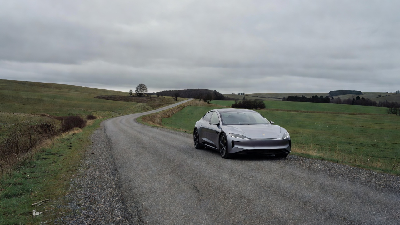Electric car parked beside a quiet country road under an overcast sky